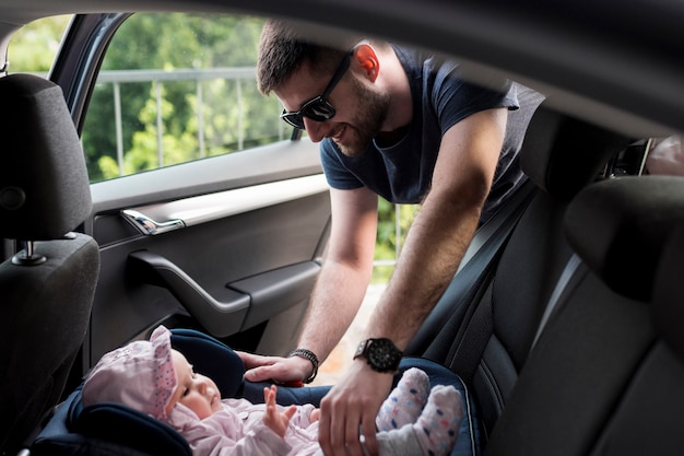 Photo adult man taking baby out of childish safety seat