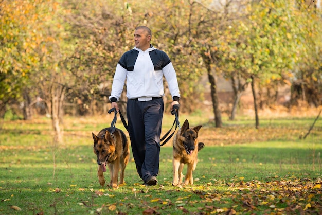 彼の犬と一緒に屋外を歩く大人の男ジャーマンシェパード