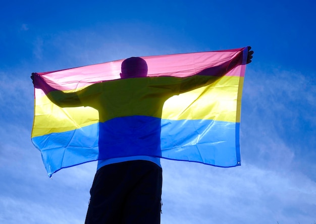 взрослый мужчина с бисексуальным флагом в солнечный день.