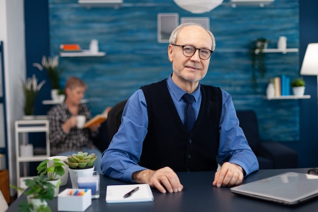 Adult man with gray hair looking pensive at camera wearing glasses