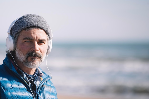 Adult man with headphones on the beach copy space