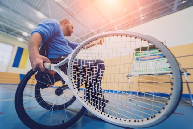 휠체어를 사용하여 실내 테니스 코트에서 테니스를 치는 신체 장애가 있는 성인 남성