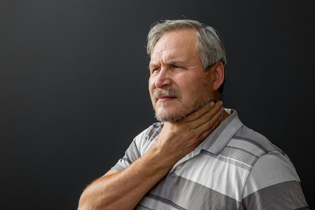 Adult man with sore throat on black background