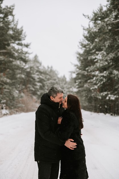 Взрослый мужчина и женщина на фоне зимнего заснеженного соснового леса
