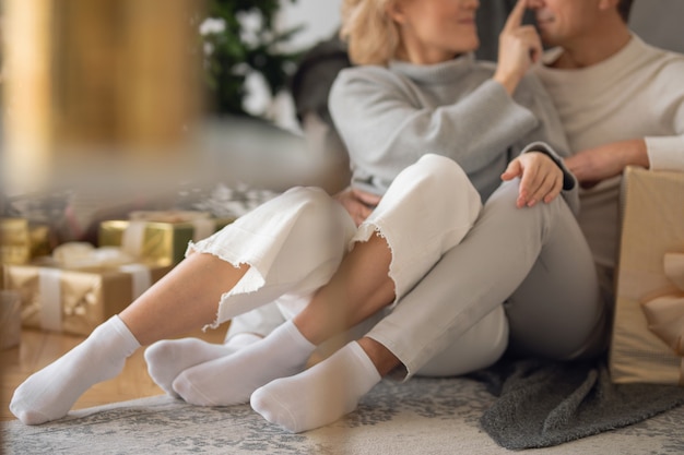 adult man and woman sit on the floor near the couch and hug