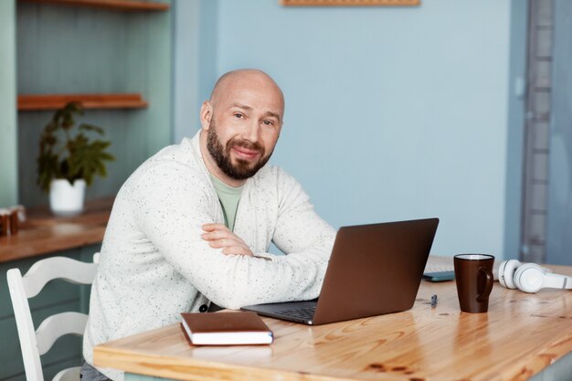 An adult man working at a computer in the kitchen