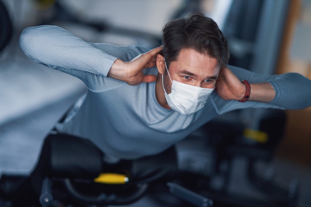 Adult man working out in a gym in mask due to covid-19