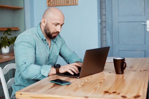 Un uomo adulto lavora al computer durante il caffè del mattino, lavora a casa