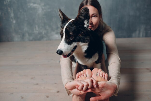 Corgi 개 애완 동물과 함께 거실에서 집에서 요가 하 고 성인 성숙한 여자