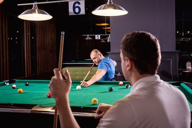 Adult men with disabilities in a wheelchair play billiards in the club