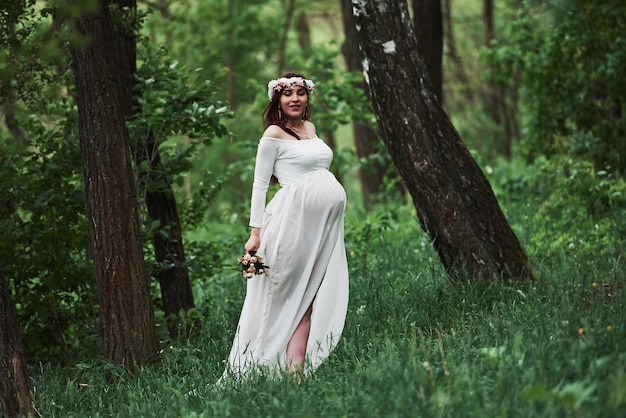 Adult mother. Beautiful pregnant woman in dress have a walk outdoors. Positive brunette