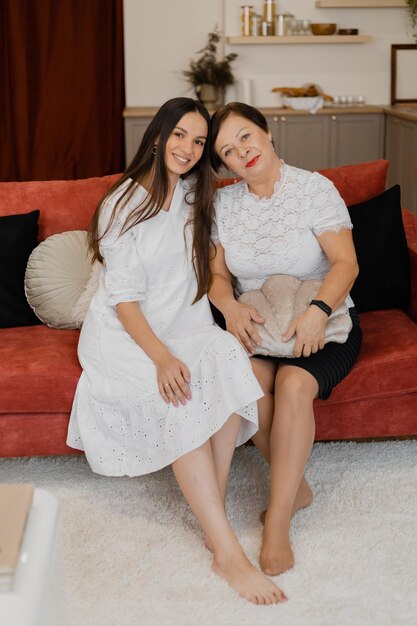 Adult mother and daughter sit on the sofa