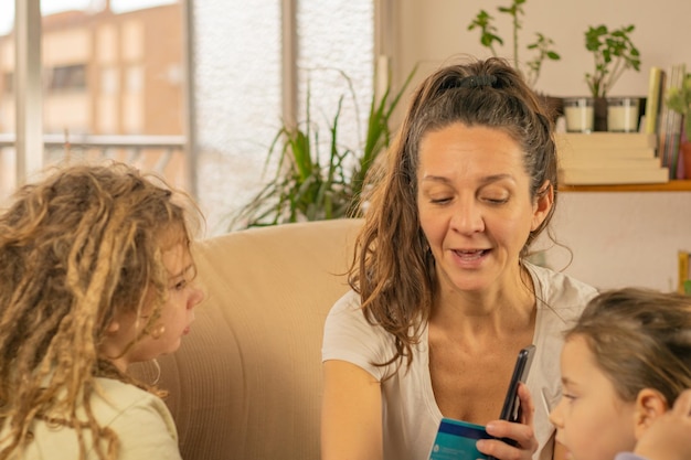 Photo an adult mother educates her little children with dreadlocks about finances there is a bank card