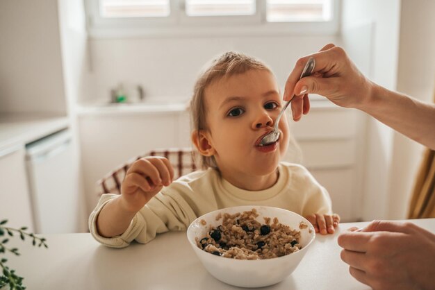 Adult person feeding porridge to a child