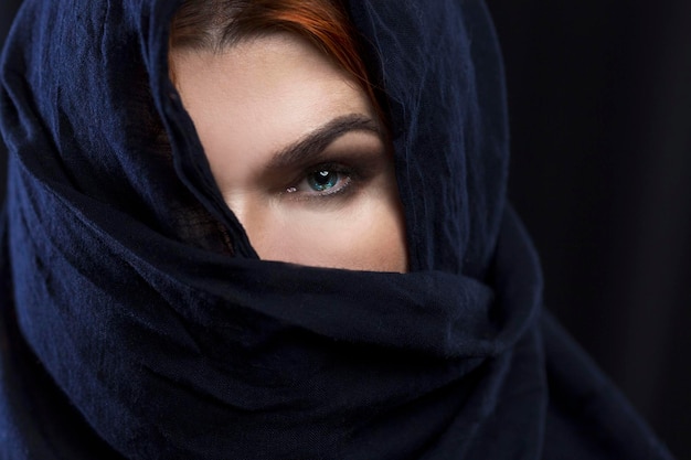 An adult redhaired woman covered one eye with a handkerchief Religion traditions and culture Closeup