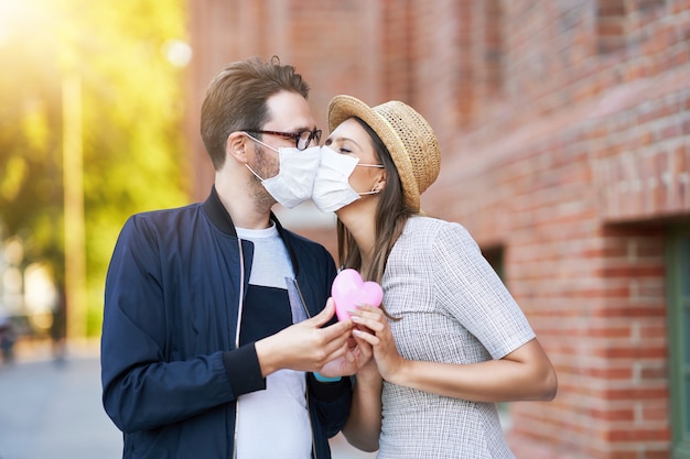 adult romantic couple wearing masks on the walk in the city