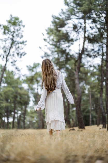 Adult Spanish woman wearing a white dress and walking in a meadow on a gloomy day