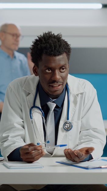 Adult specialist talking to patient with horizontal green screen on laptop in medical office. young medic having device with chroma key isolated background and mockup template on desk