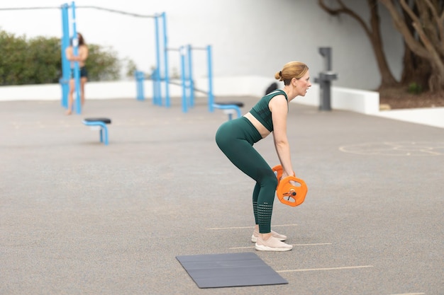 Взрослая спортивная женщина тренируется с гантелью