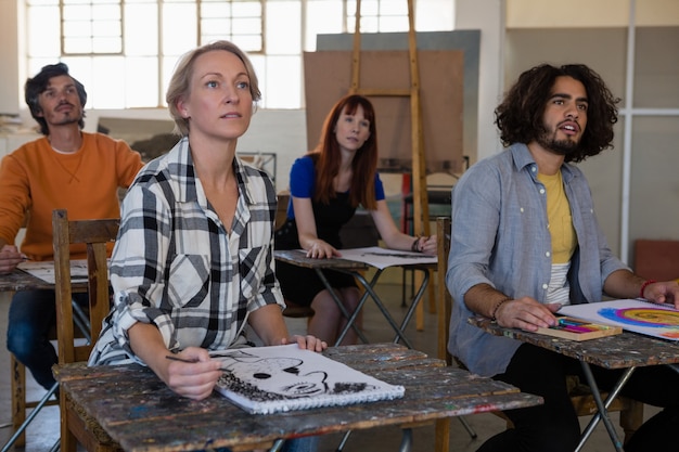 Adult students looking away while sitting at table