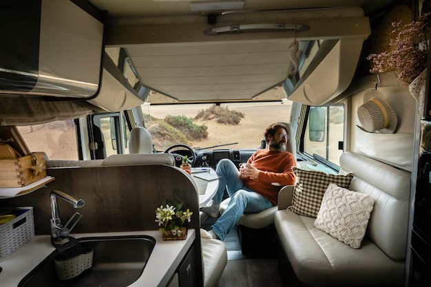 Adult traveler man sit down inside modern cozy mobile home
camper van looking nature outside travel and vanlife lifestyle for
alternative free people camper van interior and holiday
vacation