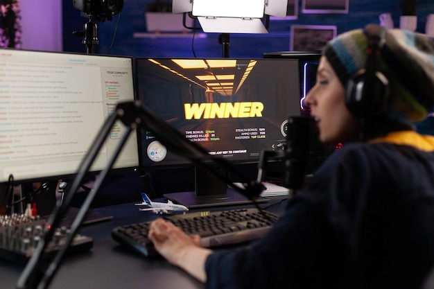 Adult winning video games on online stream with live chat.
woman streaming gameplay on computer with hmicrophone and
headphones. person broadcasting while she plays video game.