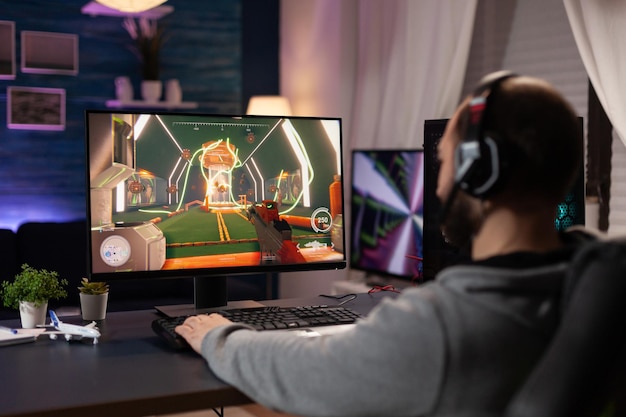 Photo adult with headphones playing video games on computer. man wearing headset, using keyboard and mousepad to play online video game on monitor with gaming equipment. modern player