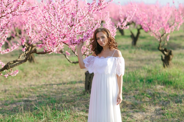 Adult woman 35 years old in a garden with trees blooming pink