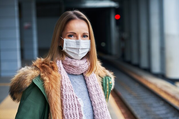 Covid-19 제한으로 인해 마스크를 쓰고 기차역에서 성인 여성