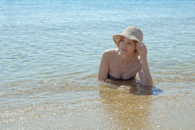 An adult woman in a bathing suit lies in sea water Summer vacation on the sea coast