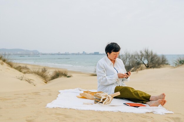 봄 여름 해변에 있는 성인 여성은 피크닉 구매를 위해 온라인 제품을 주문합니다. 빠른 배송