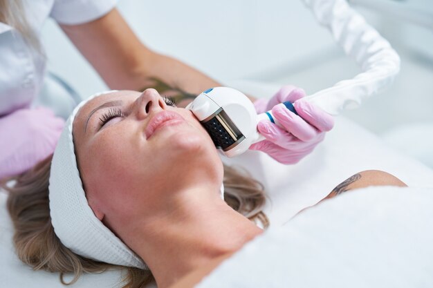 Adult woman in beauty salon undergoing face hydrogen purification