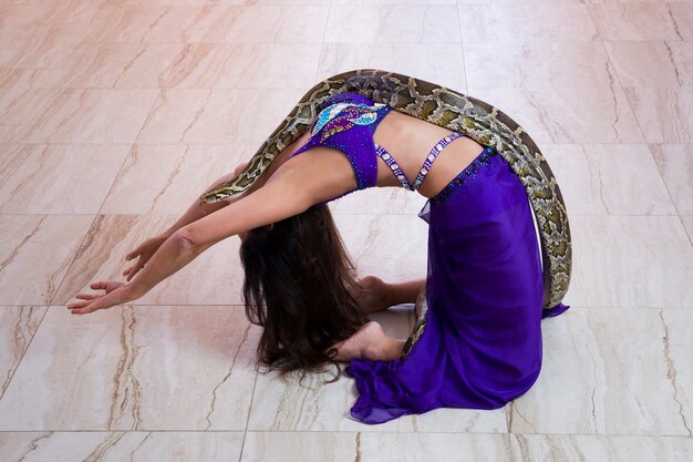 Adult woman in blue stage costume performs with big snake