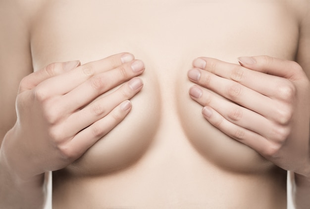 Adult woman examining breast for lumps, signs of breast cancer. 