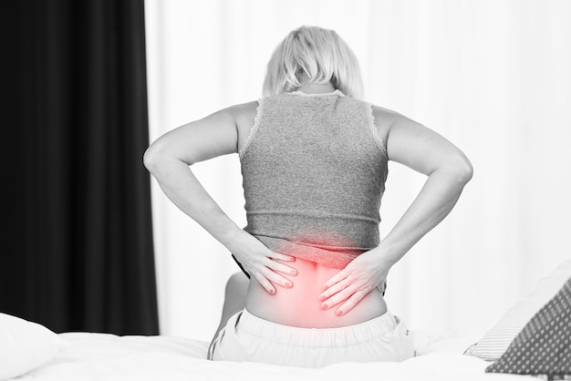Взрослая женщина чувствует себя неуютно, страдая от боли в спине