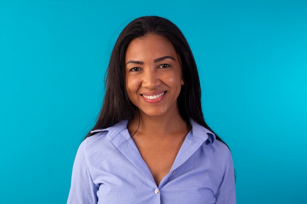 Adult woman in formal wear, wearing blue shirt and jeans in studio photo with blue background.