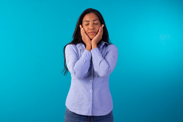 Adult woman in formal wear, wearing blue shirt and jeans in studio photo with blue background.