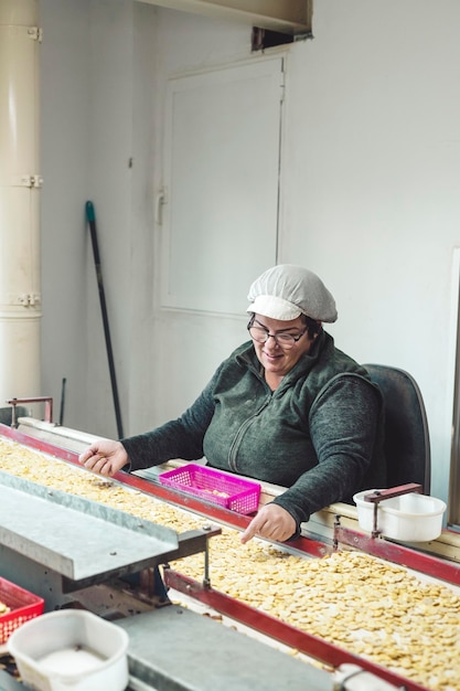 Adult woman in her place of rabajo selecting beans in front of a conveyor belt