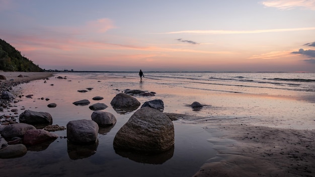 An adult woman is alone on the sea beach during the order. rear and side view