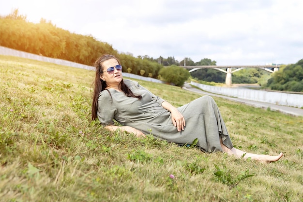 Взрослая женщина отдыхает лежа на траве на открытом воздухе в парке