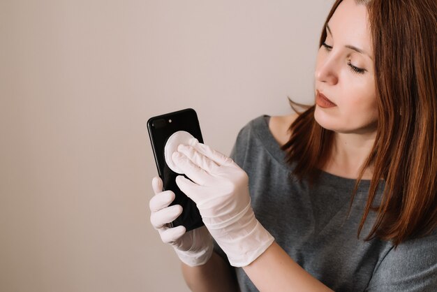 写真 大人の女性が携帯電話にアルコール、消毒剤スプレーをスプレーし、covid-19ウイルスの感染を防ぎます