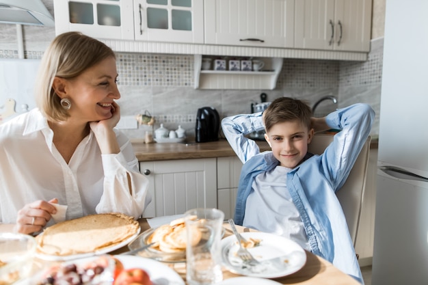 An adult woman in the kitchen looks like a child eats