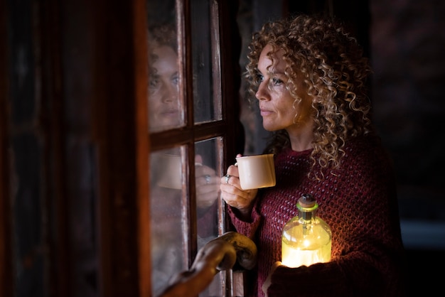 Adult woman look outside the window at home in winter