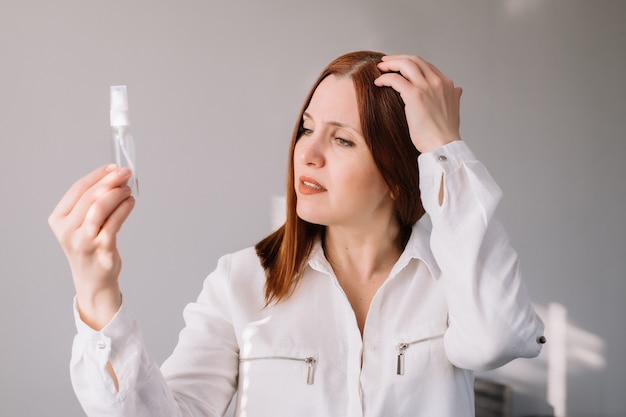 Adult woman looking and check at the sanitizes gel at home. Woman uses an antibacterial hand cleaner.