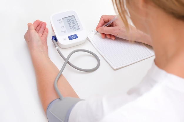 Adult woman measures blood pressure, white background. arterial hypotension.