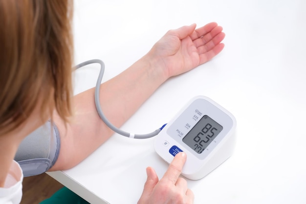 Adult woman measures blood pressure, white background. arterial hypotension.