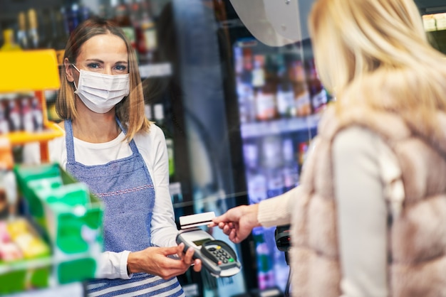 Donna adulta in maschera medica che fa la spesa per la spesa?