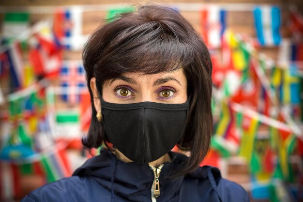 Adult woman in a medical mask on a wall background with a flag close-up