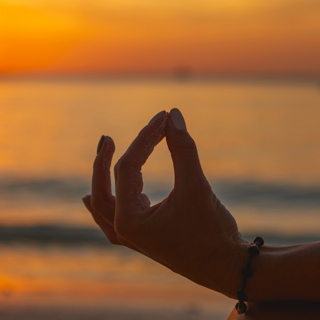 Photo adult woman do meditation on the ocean beach at sunset ãâ close up