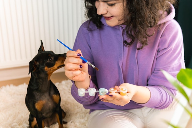 ペットを飼っている人の近くでペットのミニチュアピンチャーを屋内で数字で描いている大人の女性